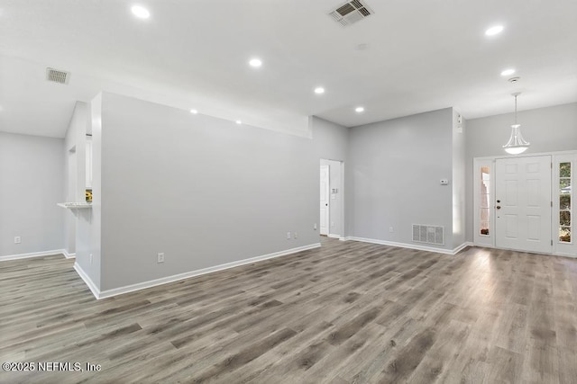 unfurnished living room featuring visible vents and wood finished floors