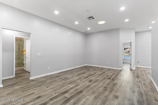 spare room with baseboards, wood finished floors, visible vents, and recessed lighting