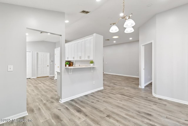 kitchen with light countertops, visible vents, light wood-style floors, white cabinets, and a chandelier