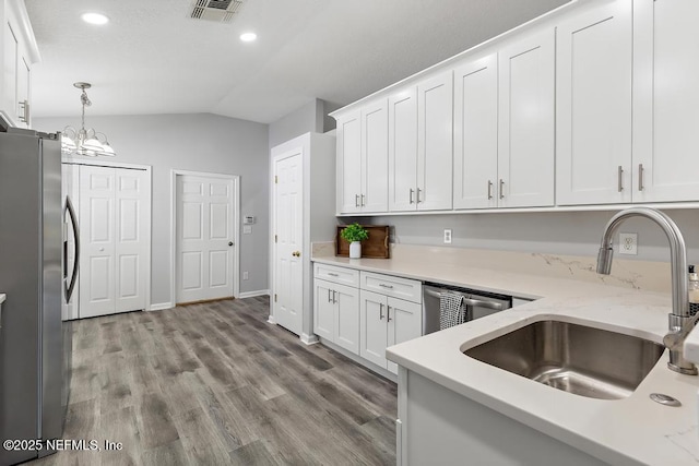 kitchen with stainless steel appliances, a sink, visible vents, white cabinets, and vaulted ceiling