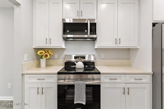 kitchen featuring appliances with stainless steel finishes, light stone countertops, and white cabinets