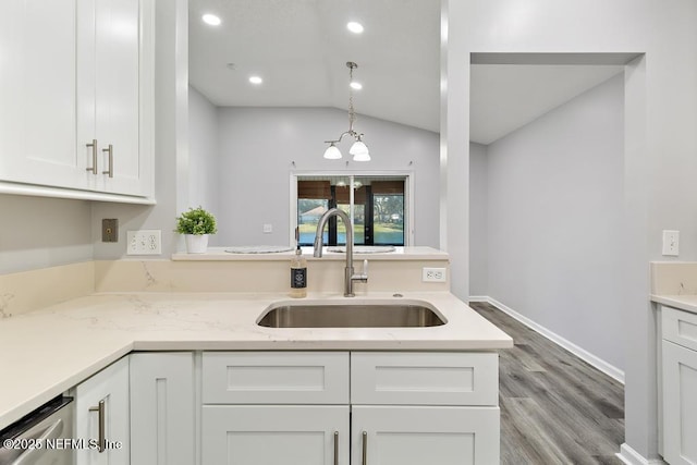 kitchen with light stone counters, lofted ceiling, white cabinets, a sink, and dishwasher