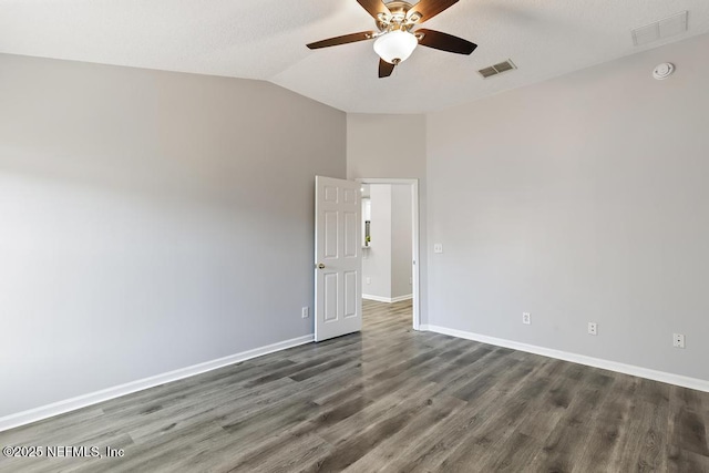 spare room with vaulted ceiling, wood finished floors, visible vents, and baseboards