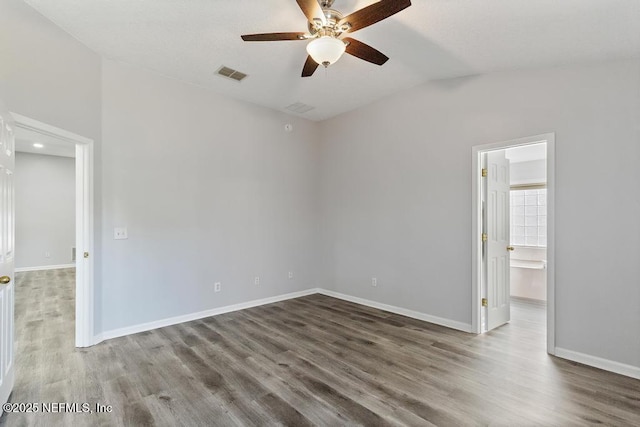 unfurnished room featuring baseboards, visible vents, ceiling fan, wood finished floors, and vaulted ceiling