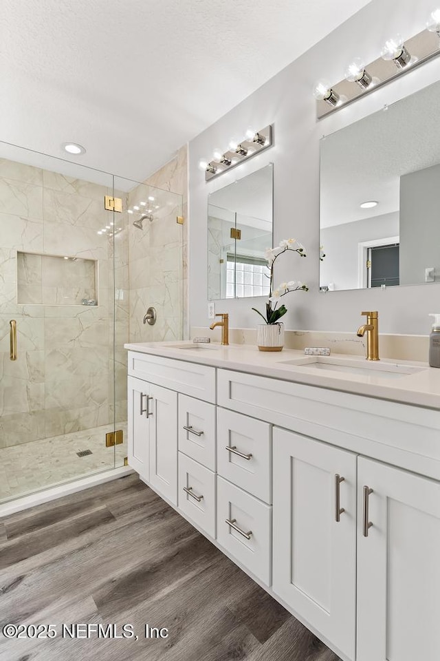 bathroom with wood finished floors, a sink, and a shower stall