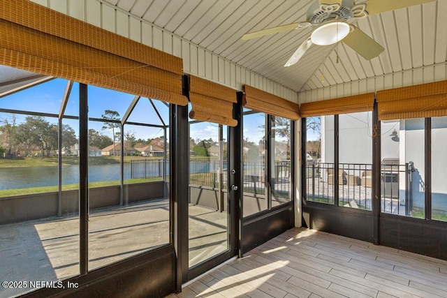 unfurnished sunroom with a water view, vaulted ceiling, and a ceiling fan