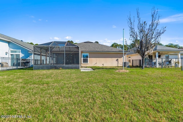 rear view of house with a lanai, fence, central AC unit, and a lawn