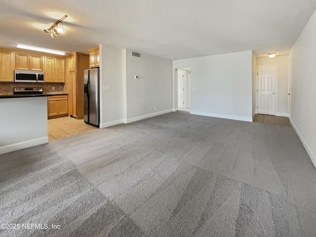 unfurnished living room featuring light colored carpet, visible vents, light tile patterned flooring, a textured ceiling, and baseboards