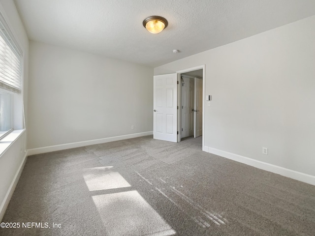 carpeted spare room with baseboards and a textured ceiling