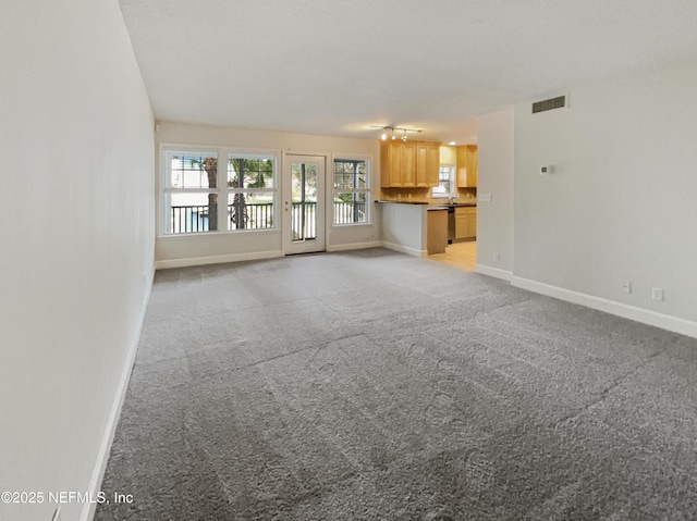 unfurnished living room featuring baseboards, visible vents, and light colored carpet