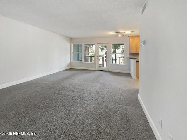 unfurnished living room featuring carpet, visible vents, and baseboards