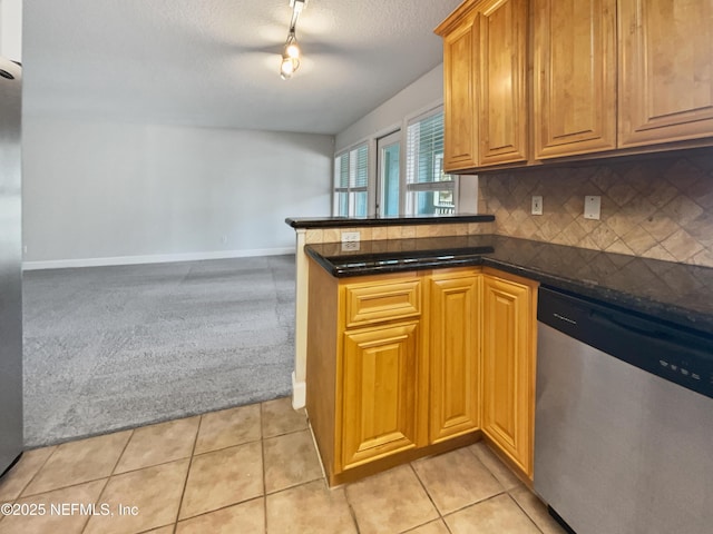 kitchen with light tile patterned flooring, backsplash, dishwasher, and light colored carpet