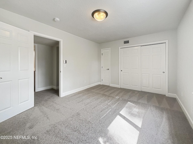 unfurnished bedroom with carpet floors, a closet, a textured ceiling, and baseboards