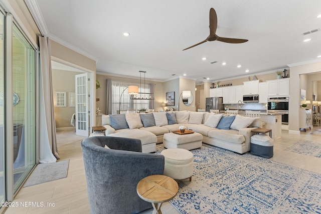 living area featuring light wood finished floors, visible vents, ornamental molding, ceiling fan with notable chandelier, and recessed lighting