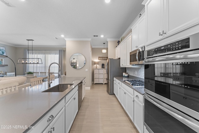 kitchen with tasteful backsplash, visible vents, appliances with stainless steel finishes, white cabinetry, and a sink