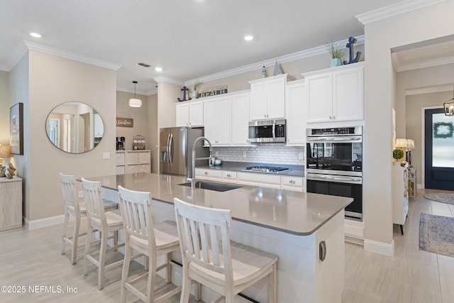 kitchen with a sink, backsplash, a breakfast bar, appliances with stainless steel finishes, and a kitchen island with sink