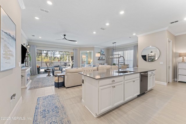 kitchen featuring visible vents, a kitchen island with sink, a sink, white cabinetry, and open floor plan