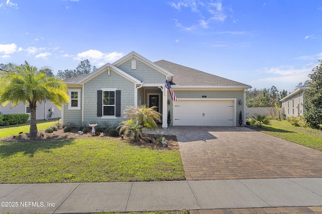 view of front of property with decorative driveway, a garage, a front lawn, and fence