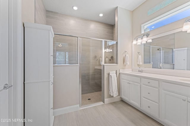 full bathroom with double vanity, a stall shower, and a sink