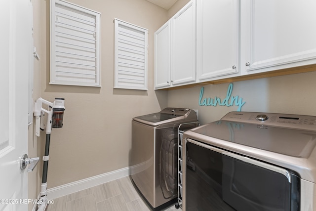 washroom featuring washing machine and clothes dryer, cabinet space, and baseboards