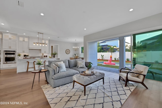 living area with a chandelier, light wood finished floors, visible vents, and recessed lighting