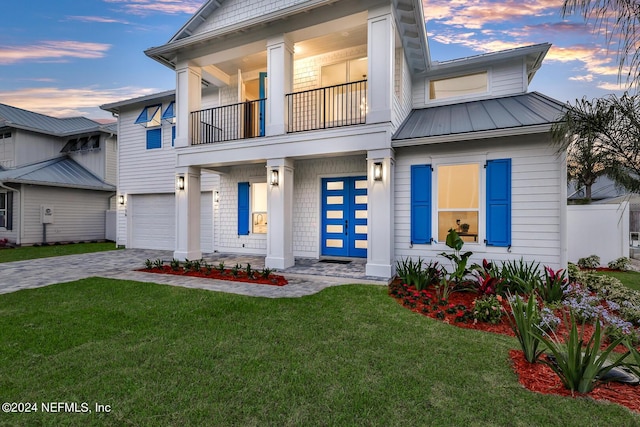 view of front of property with decorative driveway, a standing seam roof, a balcony, and a front lawn