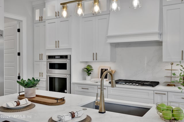 kitchen with appliances with stainless steel finishes, white cabinetry, and a sink