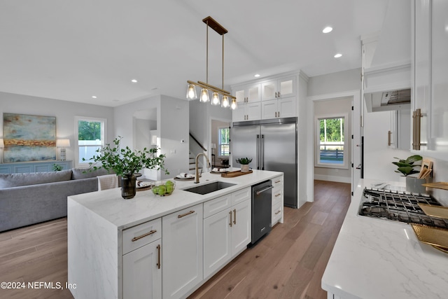 kitchen featuring appliances with stainless steel finishes, a healthy amount of sunlight, white cabinetry, and a sink