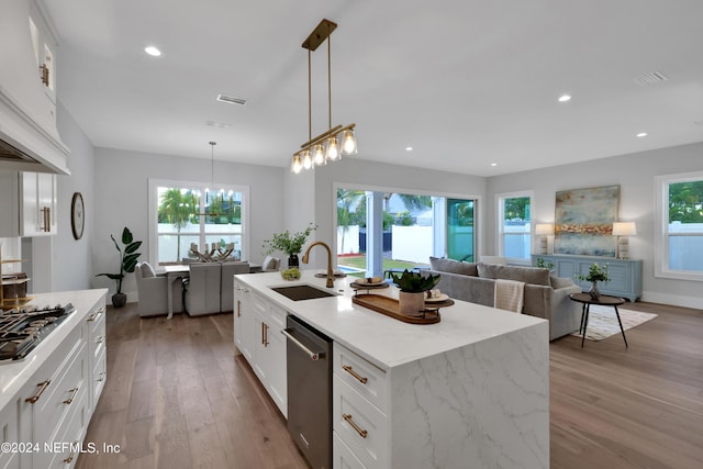 kitchen featuring appliances with stainless steel finishes, light wood-style floors, a healthy amount of sunlight, and a sink