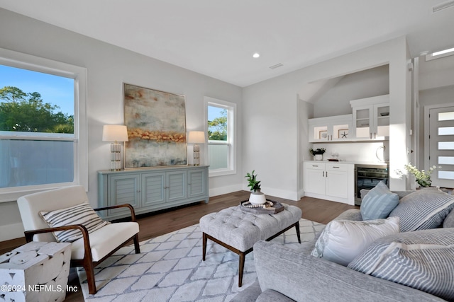 living room with beverage cooler, visible vents, baseboards, light wood-type flooring, and a bar