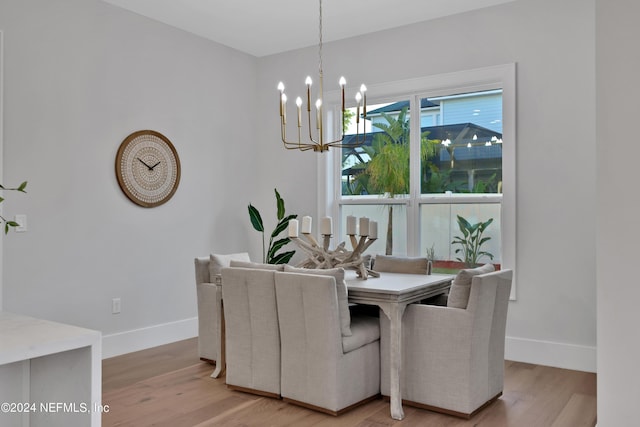 dining room with a chandelier, baseboards, and light wood finished floors