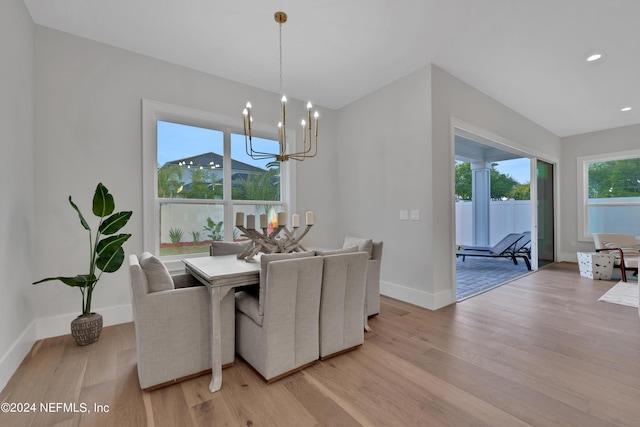 dining area with baseboards, recessed lighting, light wood-type flooring, and an inviting chandelier