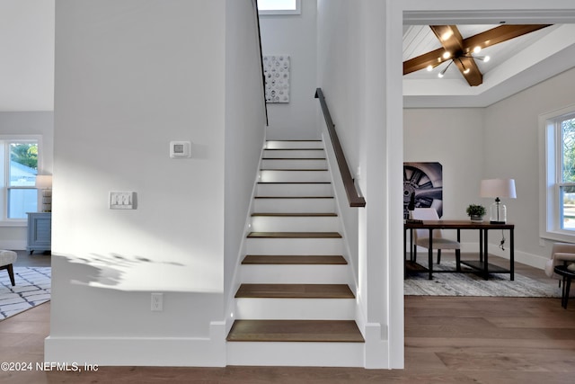 staircase featuring a notable chandelier, baseboards, and wood finished floors