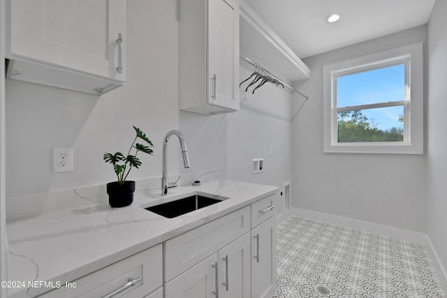 clothes washing area featuring baseboards, a sink, cabinet space, and hookup for a washing machine