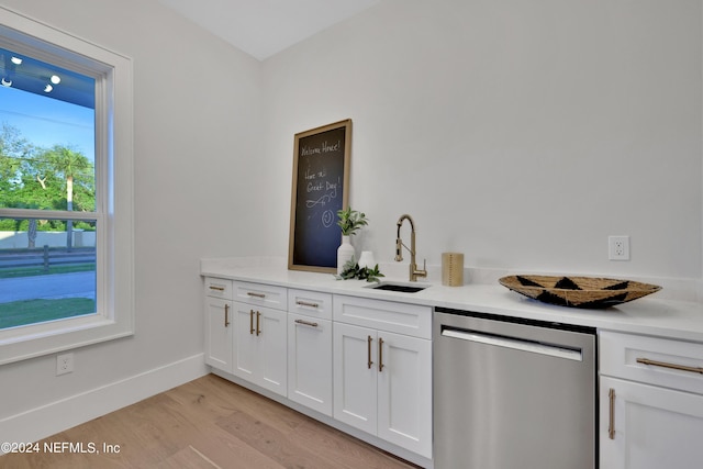 bar featuring baseboards, a sink, light wood-style flooring, and stainless steel dishwasher