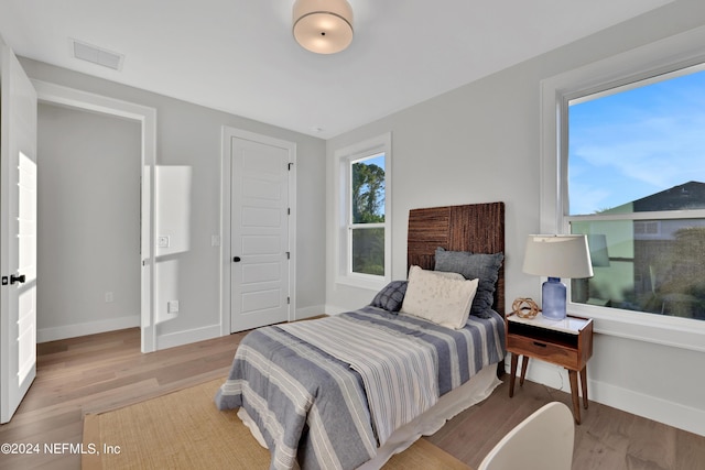 bedroom featuring baseboards, visible vents, and light wood finished floors