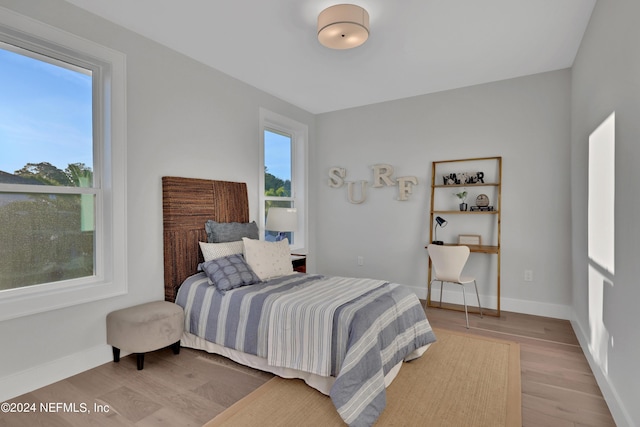 bedroom featuring multiple windows, baseboards, and wood finished floors