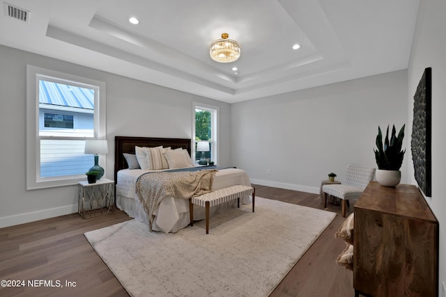 bedroom with recessed lighting, wood finished floors, visible vents, baseboards, and a tray ceiling