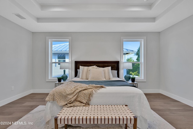 bedroom featuring visible vents, a raised ceiling, and wood finished floors