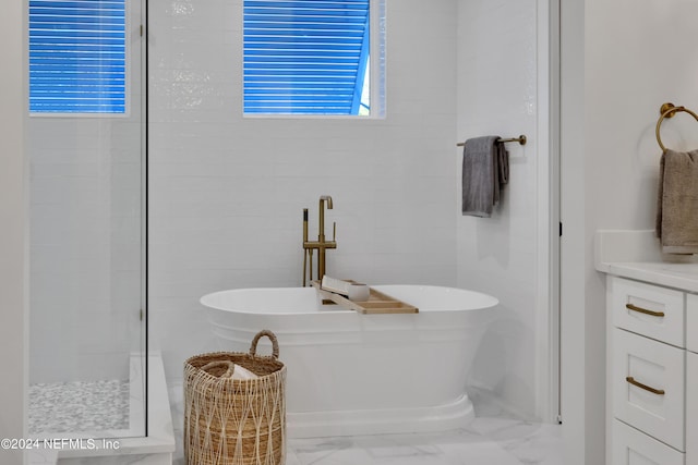 bathroom with marble finish floor, a soaking tub, and a tile shower