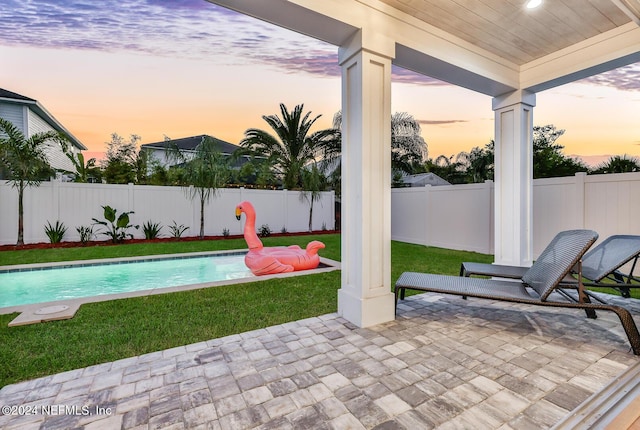 patio terrace at dusk with a lawn, a fenced backyard, and a fenced in pool