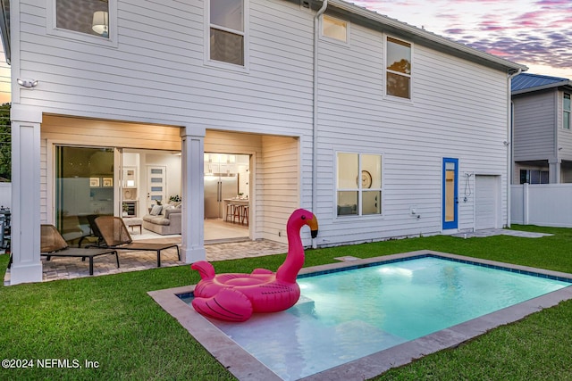 back of property featuring a fenced in pool, a patio area, a lawn, and fence