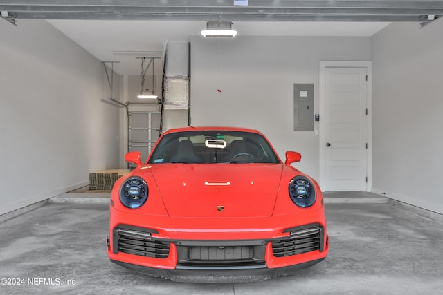 parking garage featuring electric panel, baseboards, and a garage door opener