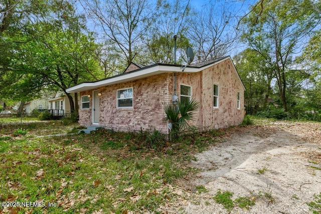 view of side of home with driveway and brick siding