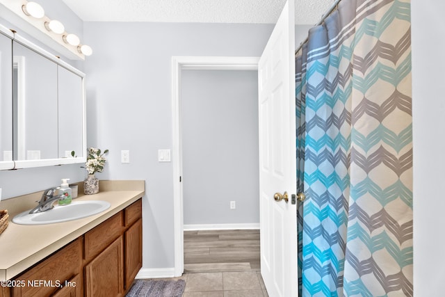 bathroom with baseboards, a shower with shower curtain, tile patterned flooring, a textured ceiling, and vanity