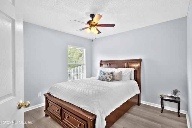 bedroom with a ceiling fan, a textured ceiling, baseboards, and wood finished floors