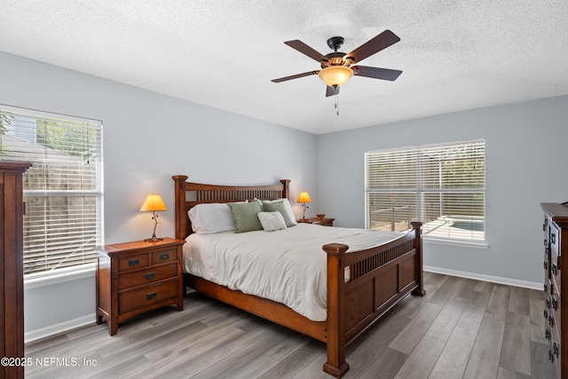 bedroom with multiple windows, wood finished floors, and baseboards