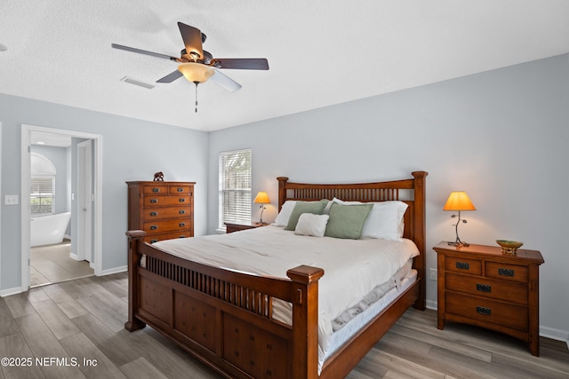 bedroom with visible vents, a ceiling fan, a textured ceiling, wood finished floors, and baseboards