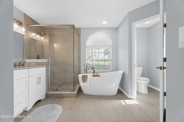 bathroom with toilet, vanity, baseboards, a soaking tub, and a shower stall