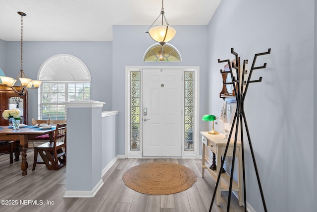 entryway featuring an inviting chandelier, wood finished floors, and baseboards